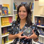 Abby Ramos Stanutz '05 poses with award recognizing her efforts to increase literacy in education.